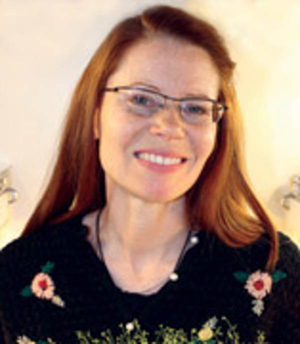 a woman with red hair and glasses smiling at the camera 